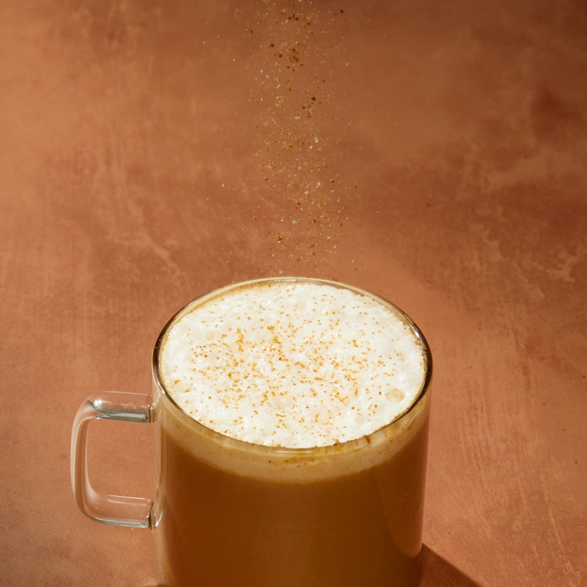 Clevr Latte Dust sprinkling onto a Clevr SuperLatte in a mug
