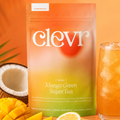 product image of clevr mango green supertea pouch with fruit adjacent coconut and mango and a drinking glass filled with iced tea