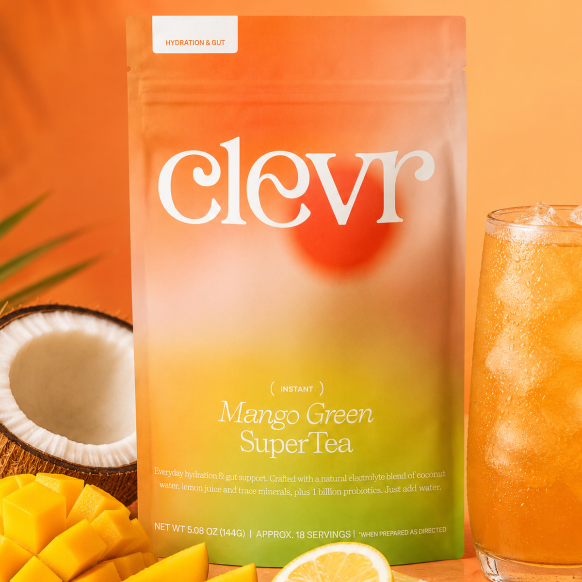 product image of clevr mango green supertea pouch with fruit adjacent coconut and mango and a drinking glass filled with iced tea